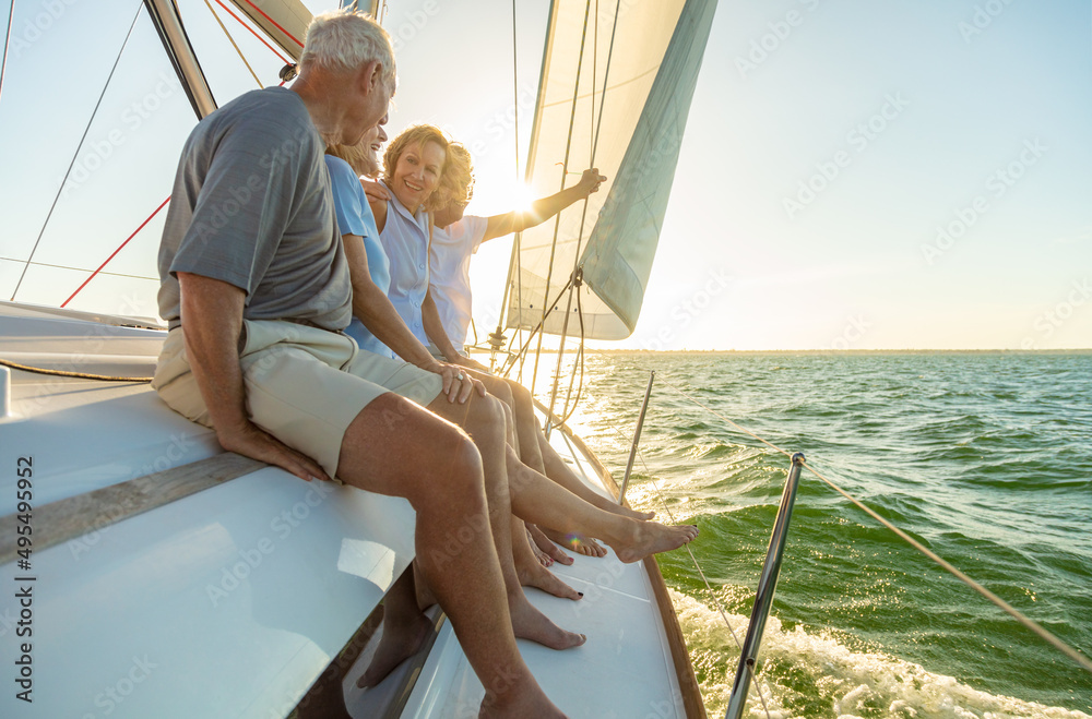 Senior-couples-enjoying-a-relaxing-sailing-trip-at-sunset-sitting-on-the-edge-of-a-boat-with-smiles- reflecting-a-carefree-and-fulfilling-lifestyle